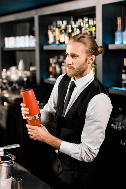 Handsome barman mixing cocktail in shaker  - Photo, Image