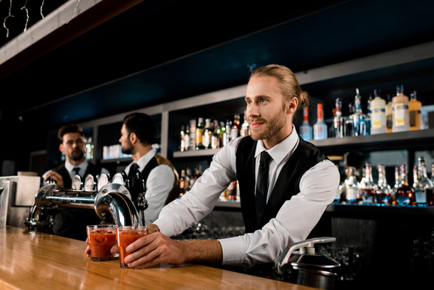 Handsome bartender serving drinks in glasses  - Photo, Image