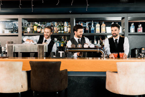 Cheerful bartenders working and smiling in bar  - Photo, Image