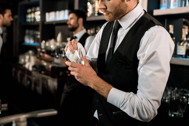 Bartender cleaning glass with white cloth in bar  - 写真・画像