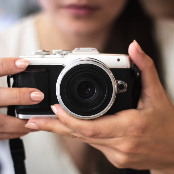 Young woman holds a compact photo camera - Fotó, kép
