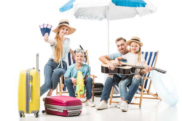 Cheerful family sitting on deck chairs with baggage on white - Foto, Imagem