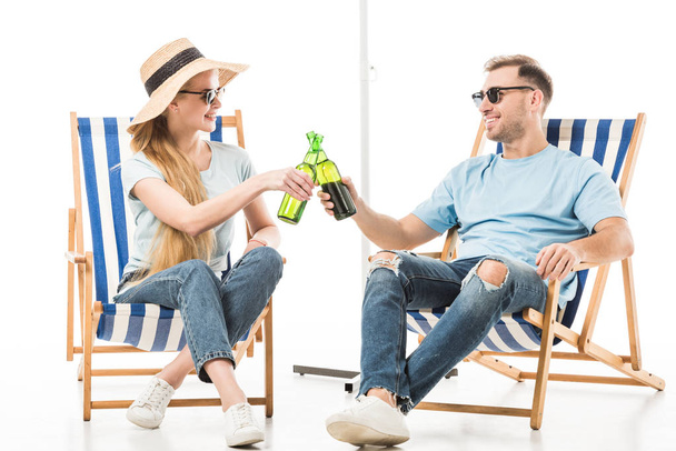 Couple sitting on deck chairs, relaxing and drinking beer isolated on white - Fotografie, Obrázek