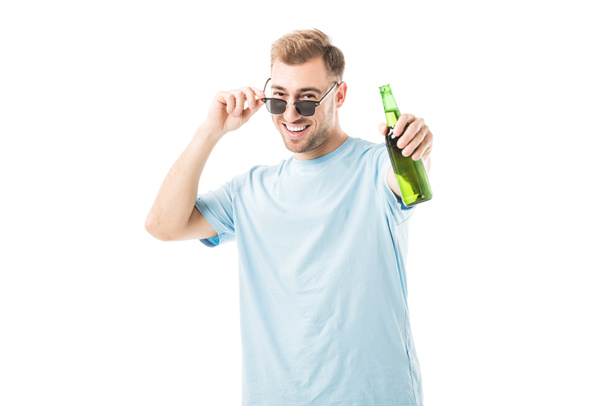 Cheerful man standing and holding bottle with beer isolated on white  - Photo, Image
