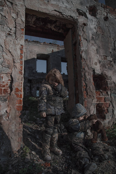portrait of little dirty homeless kids with bear toy beside abandoned building - Zdjęcie, obraz
