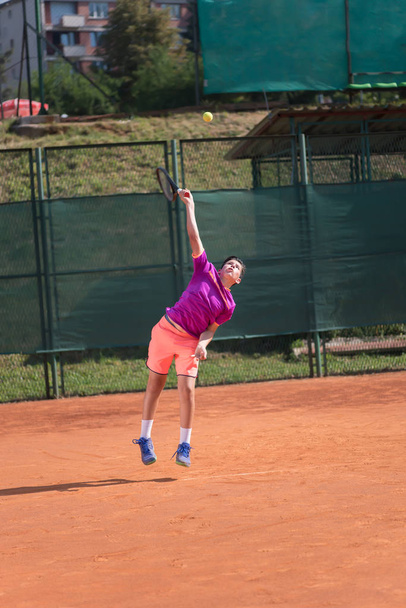 Young tennis player serving the ball - Фото, изображение