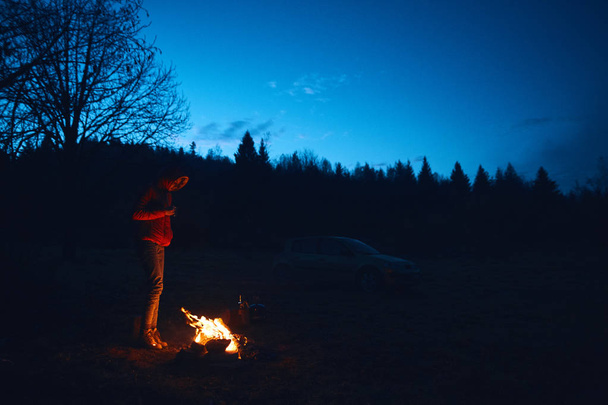 Young woman in standing near the campfire - Foto, imagen