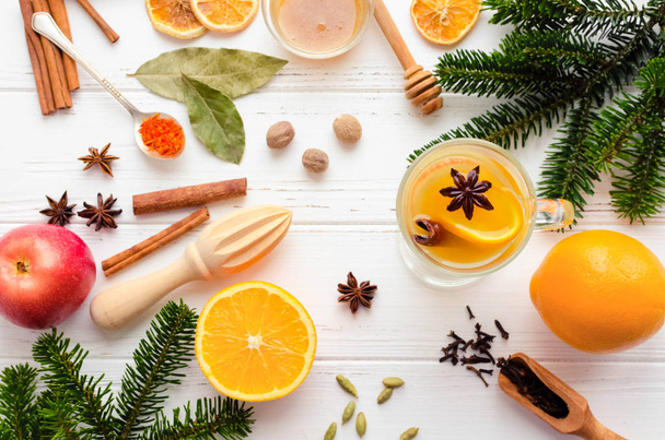 Christmas hot white mulled wine in glass with orange, honey, cinnamon sticks and star anise with ingredients on white wooden background. Spicy warm beverage. Seasonal mulled drink. Top view. - Foto, afbeelding