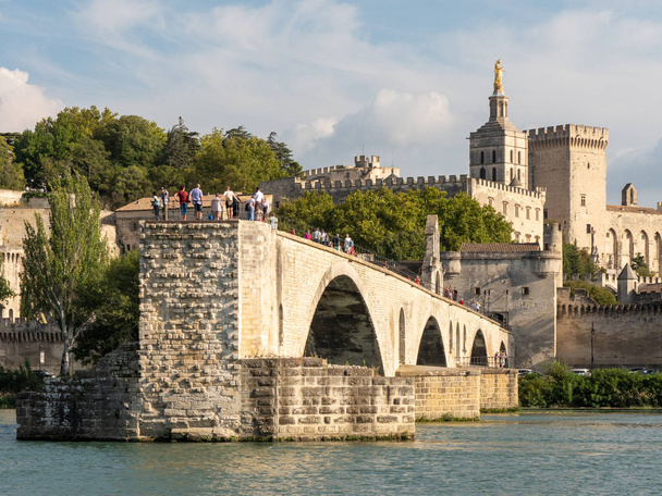Η γέφυρα της Αβινιόν και το Παπικό Παλάτι στην πόλη της Αβινιόν, νότια της Γαλλίας. Η γέφυρα και το παλάτι και χτίζονται στην μεσαιωνική εποχή. Ο ποταμός σε πρώτο πλάνο είναι ο Ρήνος. - Φωτογραφία, εικόνα