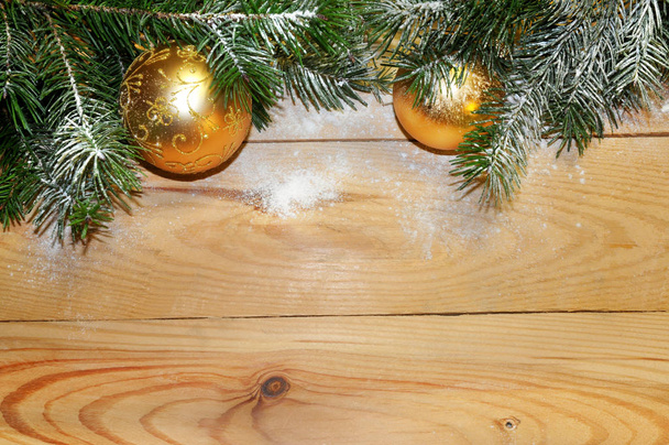 Snow-covered Christmas tree branch with Christmas balls on wood. Christmas background - Photo, Image