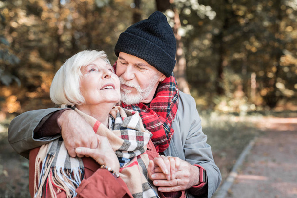 positive ältere Frau bietet ihrem Mann einen Apfel an - Foto, Bild