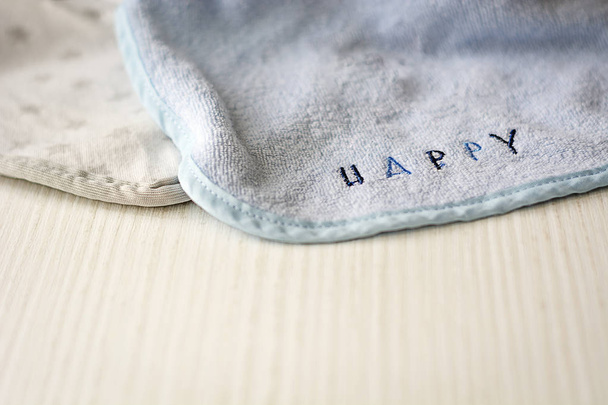 a baby bib with the word "HAPPY" resting on a white table - Photo, Image