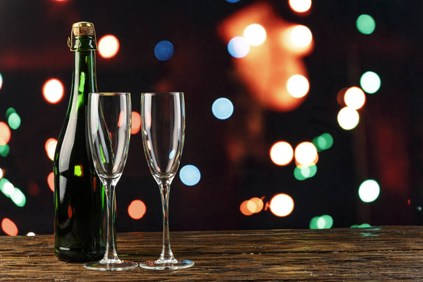 champagne in glasses and in a bottle on bokeh background. christmas background. space for tex - Фото, изображение