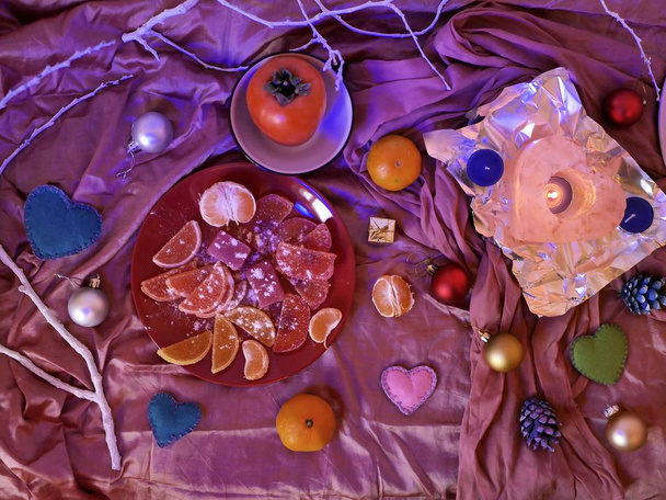 On the table on a pink cloth dishes with a variety of sweets, romantic and Christmas decor, hearts, fruits, seasonal winter holidays, Christmas, Valentine's, celebrate, top view, red, purple color - Φωτογραφία, εικόνα