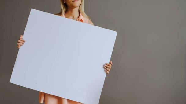 A pretty blonde girl with a whiteboard, close view, grey background - Foto, Imagem