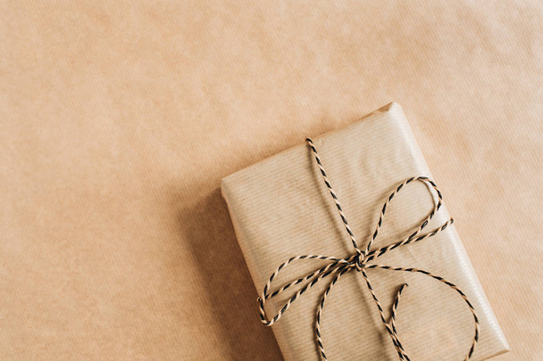 De doos van de gift met strik op ambachtelijke papier achtergrond. Kerst / Nieuwjaar minimale samenstelling. Flatlay, bovenaanzicht. - Foto, afbeelding