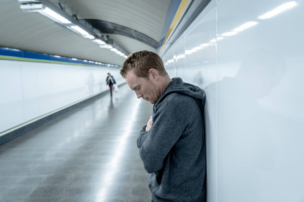 Miserable jobless young man crying Drug addict Homeless in depression stress sitting on ground street subway tunnel looking desperate leaning on wall alone in Mental disorder Emotional pain Sadness. - Fotografie, Obrázek