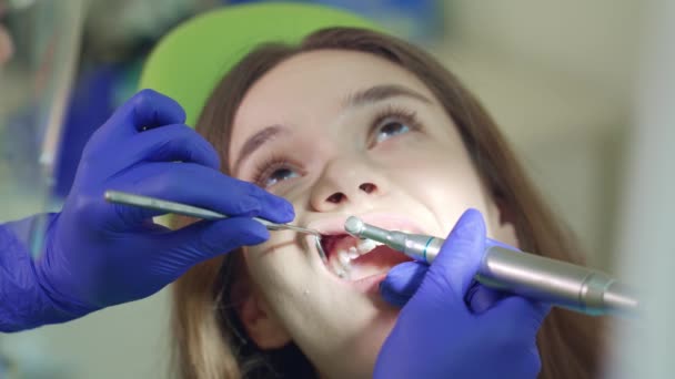 Paciente do sexo feminino em procedimento de limpeza dos dentes. Mãos de dentista trabalhando
 - Filmagem, Vídeo