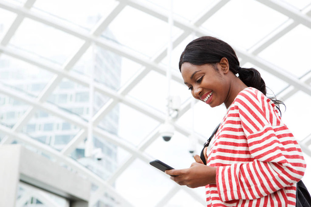 Portrait latéral rapproché d'une jeune femme afro-américaine regardant un message texte sur un téléphone portable
 - Photo, image