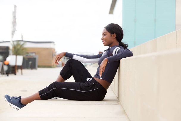 Side portrait of fit young african american sports woman sitting outside - Foto, immagini