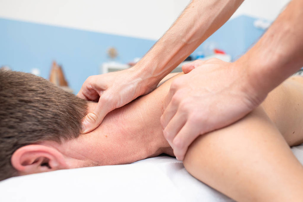 Therapeut massiert Nacken eines jungen Mannes. - Foto, Bild