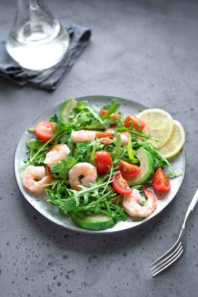 Avocado Shrimp Salad with Arugula and Tomatoes on grey stone background, close up. Healthy diet green salad with Shrimps (prawns), avocado, cherry tomato and arugula. - 写真・画像