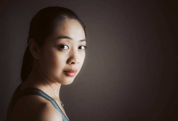 Close up face portrait of Asian woman in low light studio. - Фото, изображение