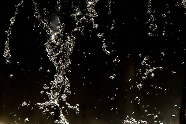 Water splash in dark with a drops of water flying, defocused bokeh. - 写真・画像