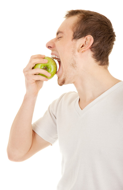 Young man bites green fresh apple - 写真・画像