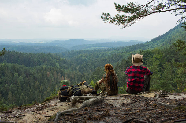 Couple of travelers standing on the cliff and watching beautiful mountains and forest  - Фото, зображення