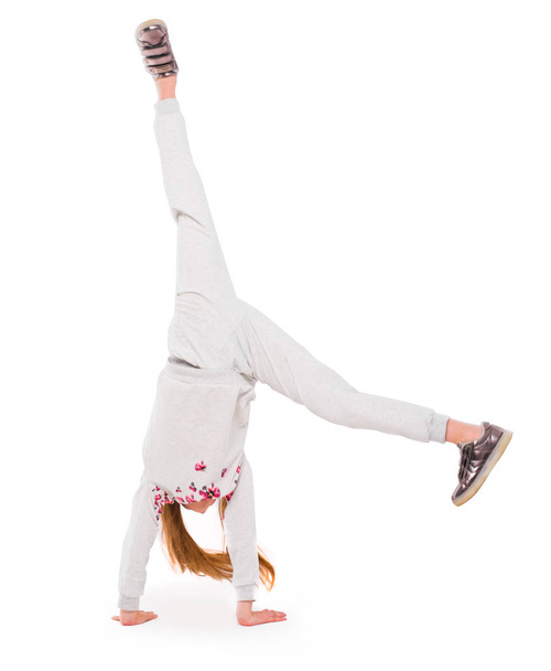 Active little girl on white backgroung doing a handstand - Foto, immagini