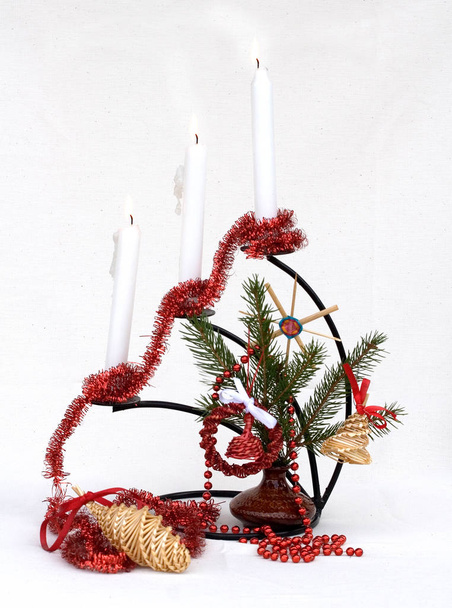 Tannenzweige mit rotem Weihnachtsschmuck und brennenden Kerzen auf weißem Hintergrund - Foto, Bild