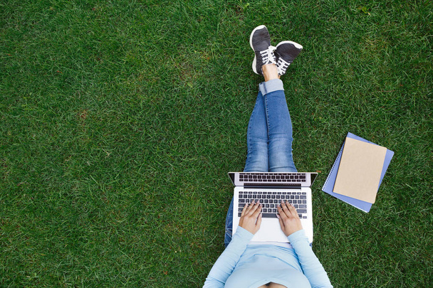 Top view of woman sitting in park on the green grass with laptop - Foto, Bild