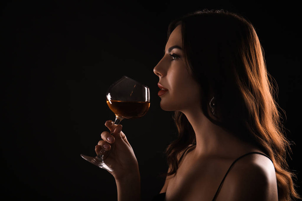 Gyönyörű fiatal nő, pohár bor sötét háttér - Fotó, kép