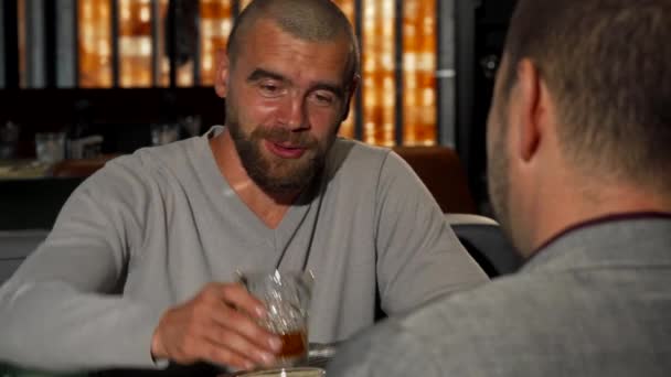 schöner Mann, der mit seinem Freund an der Bar Whiskeygläser klimpert - Filmmaterial, Video