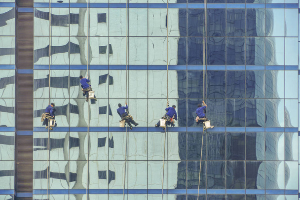 Pracownicy sprzątający okna na wysokim budynku - Zdjęcie, obraz