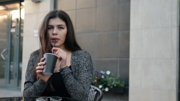 Νέοι σέξι γυναίκα που πίνει καφέ κάθεται σε ένα τραπέζι σε εξωτερικούς χώρους. - Πλάνα, βίντεο