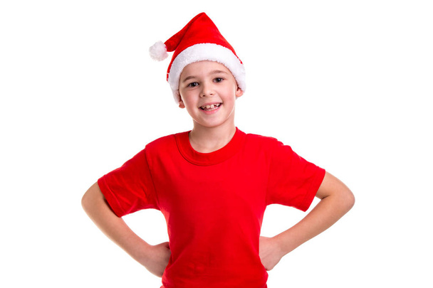 Aranyos mosolygós fiú, santa kalap a fején, a karok a derekát. Koncepció: karácsonyi vagy boldog újévi ünnep - Fotó, kép