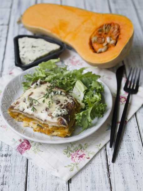 Slice of Pumpkin and Spinach Lasagne with blue cheese and salad on a White Wooden Table. Selective focus, copy space, close up - Foto, immagini
