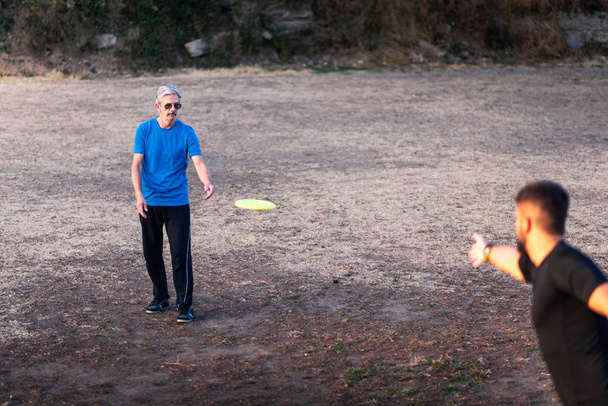 Starszy ojciec i syn gry frisbee w parku na świeżym powietrzu - Zdjęcie, obraz
