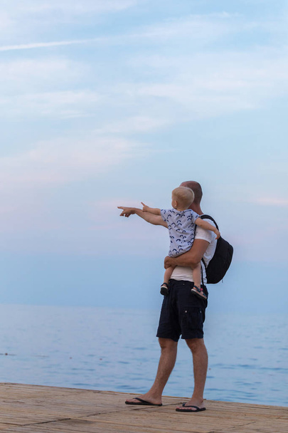 Dad holds his son in his arms and shows the sea - Fotografie, Obrázek