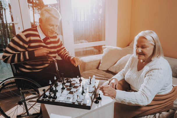 Senior Man and Woman Play Chess. Nursing Home. Man in a Wheelchair. Woman Covered with Blanket. Young Sear and Yellow Leaf. Senior Couple Hold Lees of Life. Retired People Smiling. - Fotoğraf, Görsel