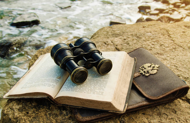 stary lornetki z przypadkiem książki i mapy, leżąc na plaży - Zdjęcie, obraz