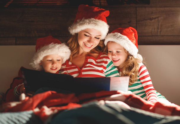 Wesołych Świąt Bożego Narodzenia! Rodzina Matka czyta dzieciom książkę przed snem w być - Zdjęcie, obraz
