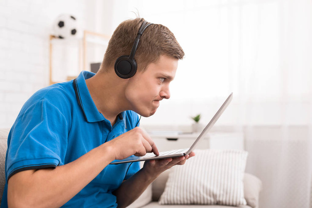 Geconcentreerde tiener jongen spelen van videogames op laptop - Foto, afbeelding