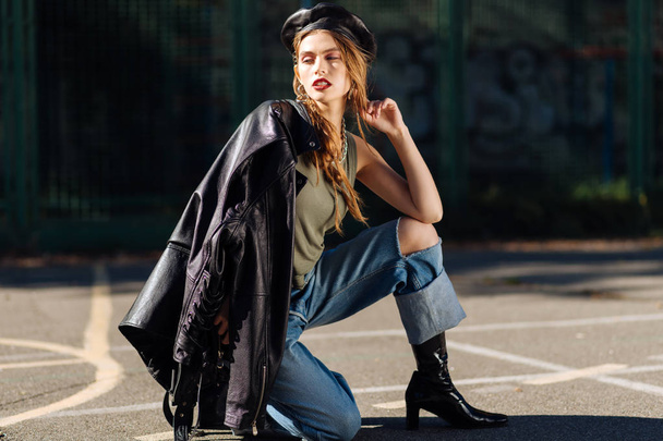 Skinny model wearing leather beret walking while shooting - Foto, Bild