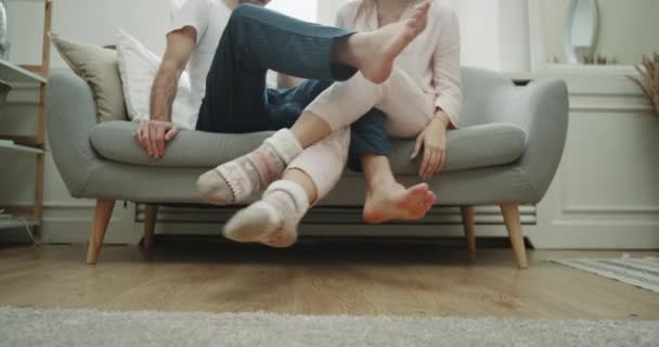 Young couple home time playing with legs spending a good time together on the sofa. - Materiał filmowy, wideo