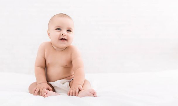 Cute baby sitting on white background, copy space - Fotó, kép