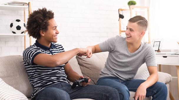 Happy vrienden geven vuisten hobbel tijdens het afspelen van video game - Foto, afbeelding