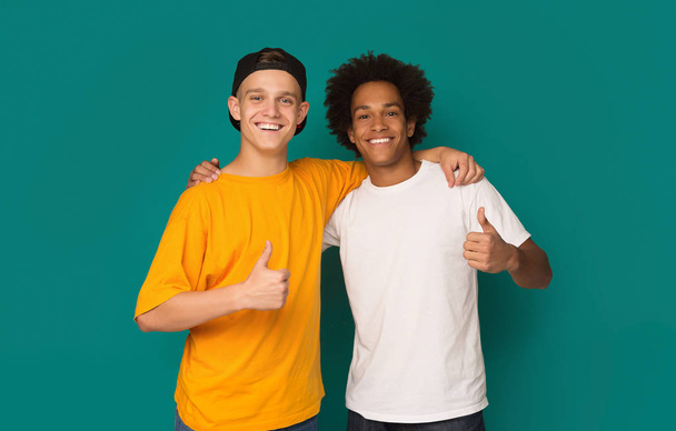 Diverse teens showing thumbs up over blue background - Foto, afbeelding